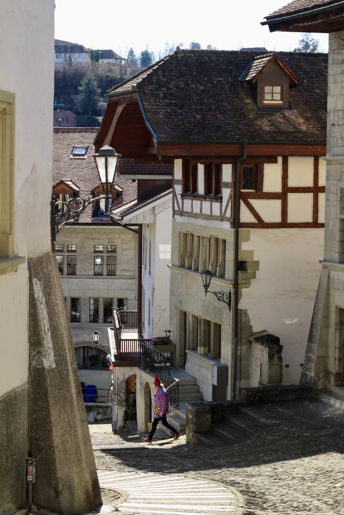 A man in costume walks down a street in Fribourg Old Town. 