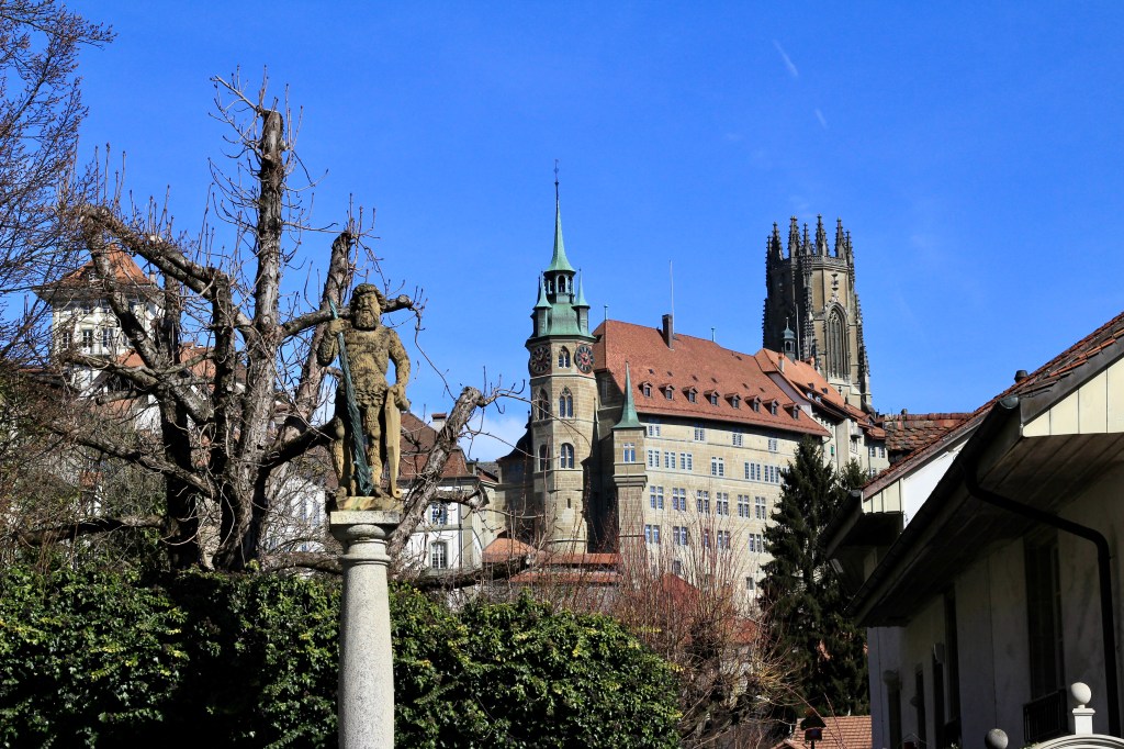 A statue and view of the cathedral spire at Fribourg, Switzerland. 