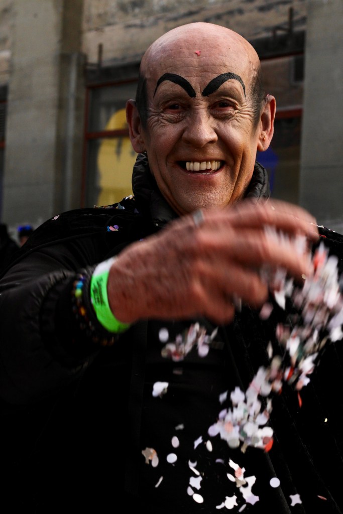 A man with painted eyebrows throws confetti. 