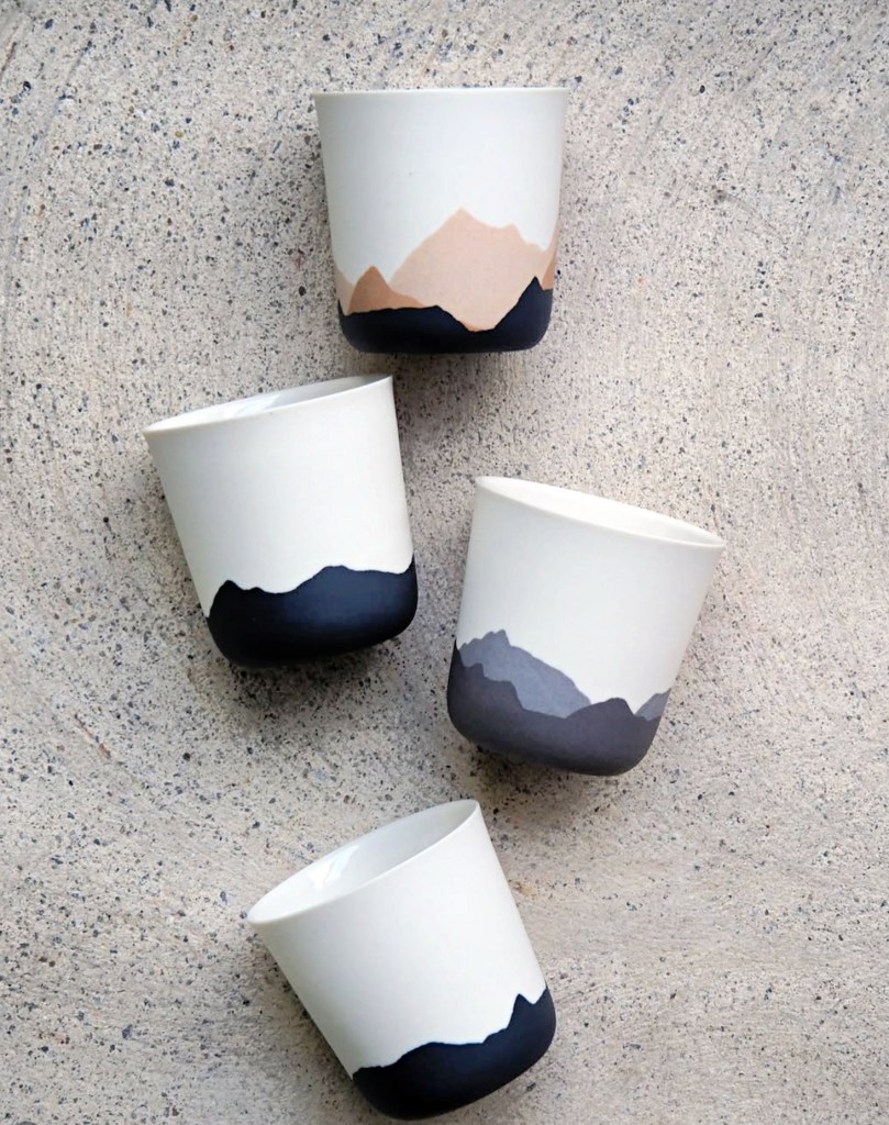Four soft coloured porcelain cups against a stone background.