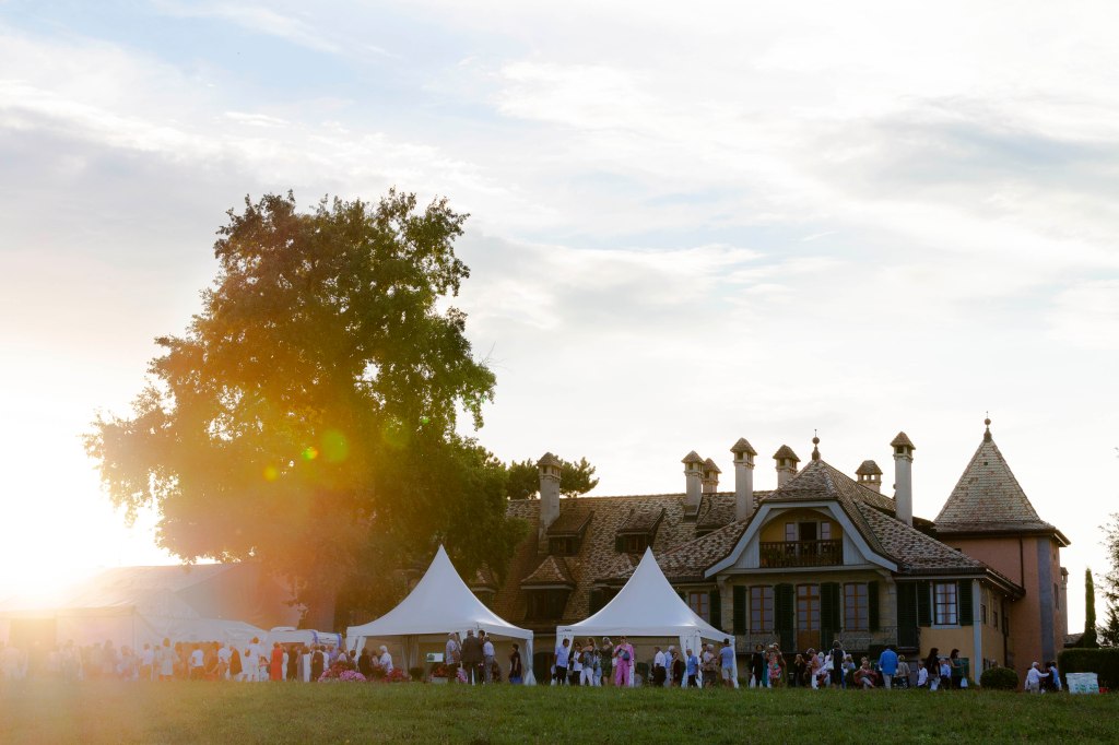 People stand before white tents set up outside the Chateau de Tannay for the classical music concerts.